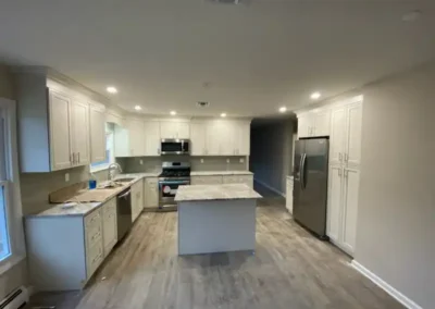 An L-shaped kitchen with a breakfast bar, stainless steel appliances, and overhead lighting.