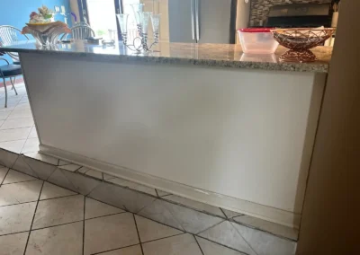 Custom white kitchen cabinets with glass-paneled doors and decorative handles.