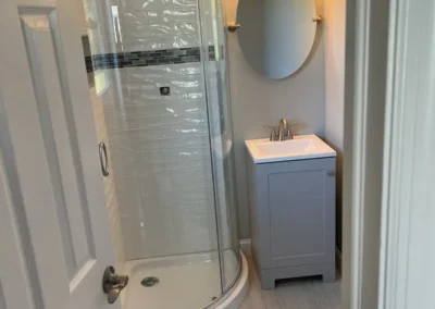A stylish bathroom showcasing a curved glass shower enclosure and elegant fixtures.